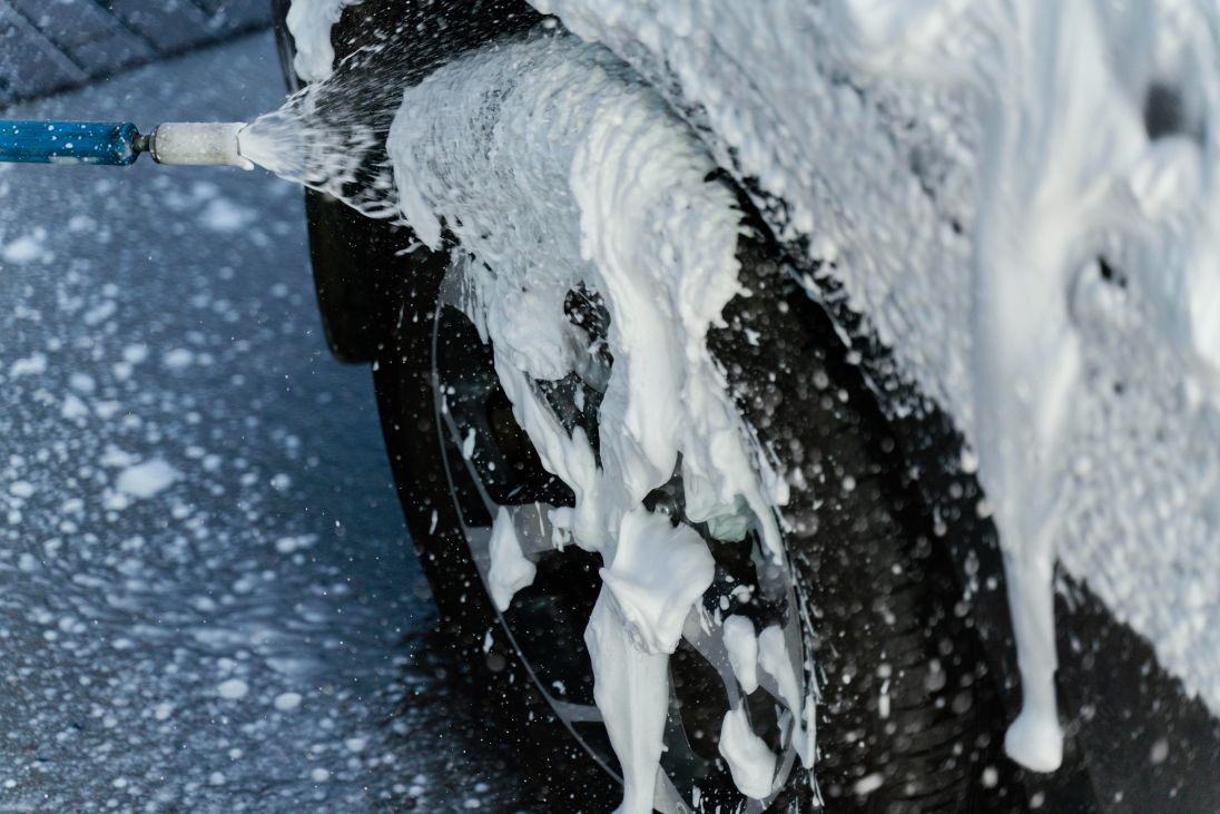 mujer lavando su coche  con espuma activa al aire libre